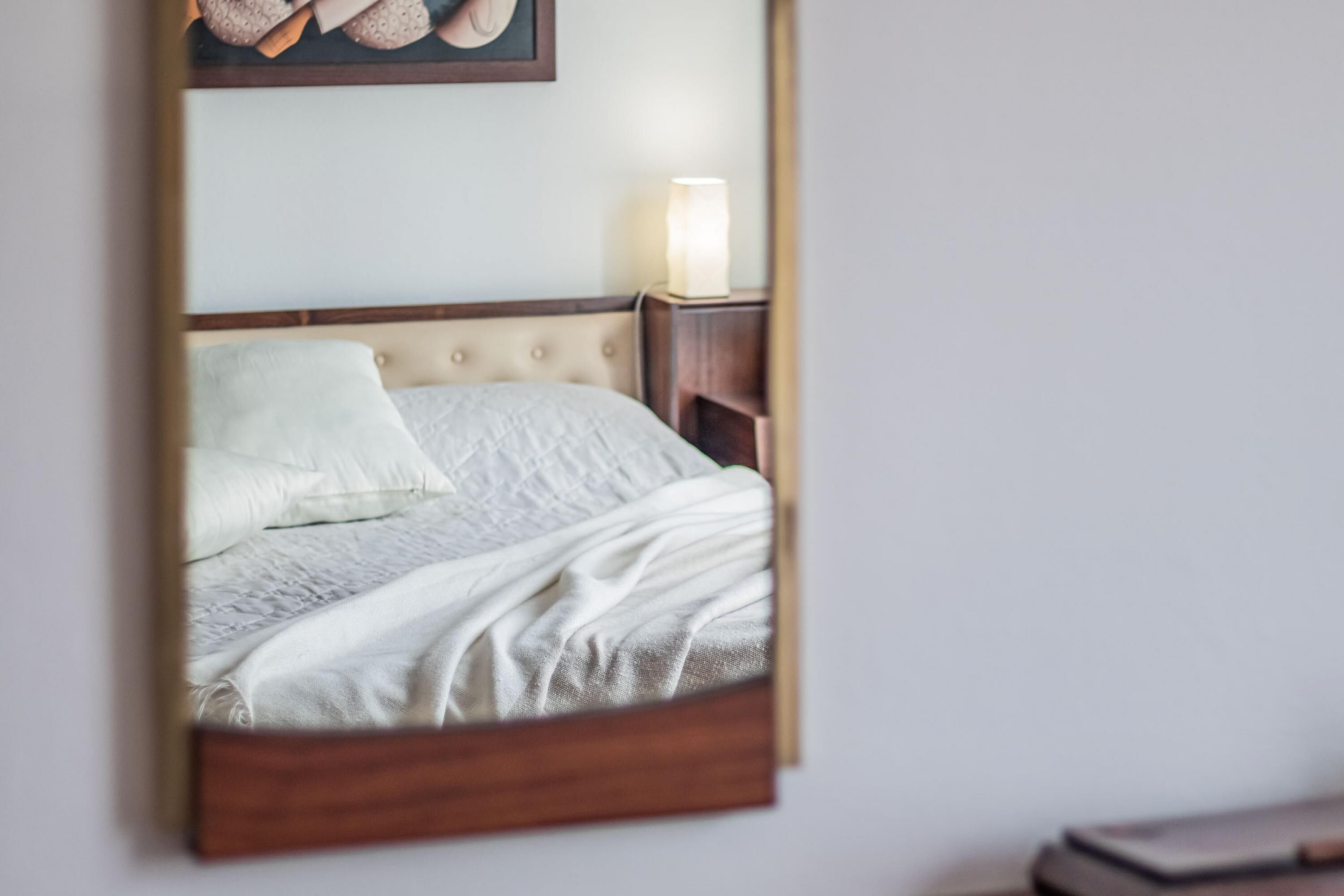 A bedroom with a bed, a nightstand, and a wall-mounted lamp.