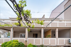 Un edificio de varios pisos con balcones, una escalera visible y un área de jardín.