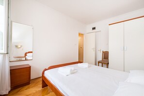Un dormitorio con una cama de madera, una mesita de noche, una silla, un armario y un espejo.