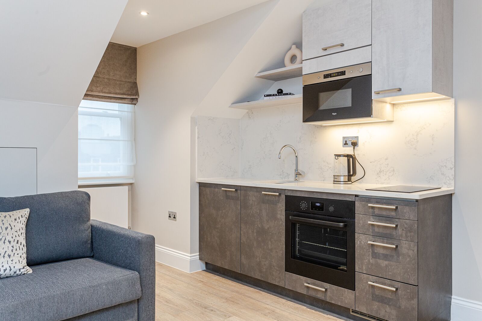 A modern kitchen with a built-in oven, microwave, and a coffee maker on the countertop.
