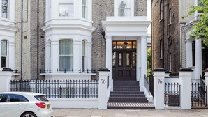 A townhouse with a black front door, white trim, and a number '76' on the gate. - Cleveland Residences Chelsea (London)