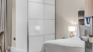 Un dormitorio moderno con una cama, un armario, un escritorio y una silla.