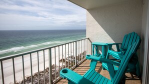 Een balkon met turquoise stoelen met uitzicht op de oceaan.