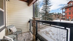 Un balcon avec un pilier en pierre, une rambarde en métal et une chaise avec un coussin.