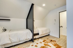 Un dormitorio con dos camas, un tapete de cuero de vaca y una puerta.