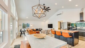 A modern kitchen with a central island, a dining area with a large table, and a cozy seating area with a fireplace. - Family-friendly Donnelly Home w/ Private Hot Tub! (Donnelly)