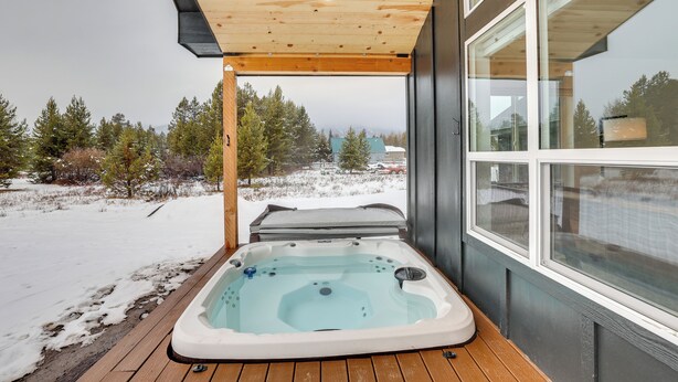 A hot tub on a wooden deck with a view of a snowy landscape and trees. - Family-friendly Donnelly Home w/ Private Hot Tub! (Donnelly)