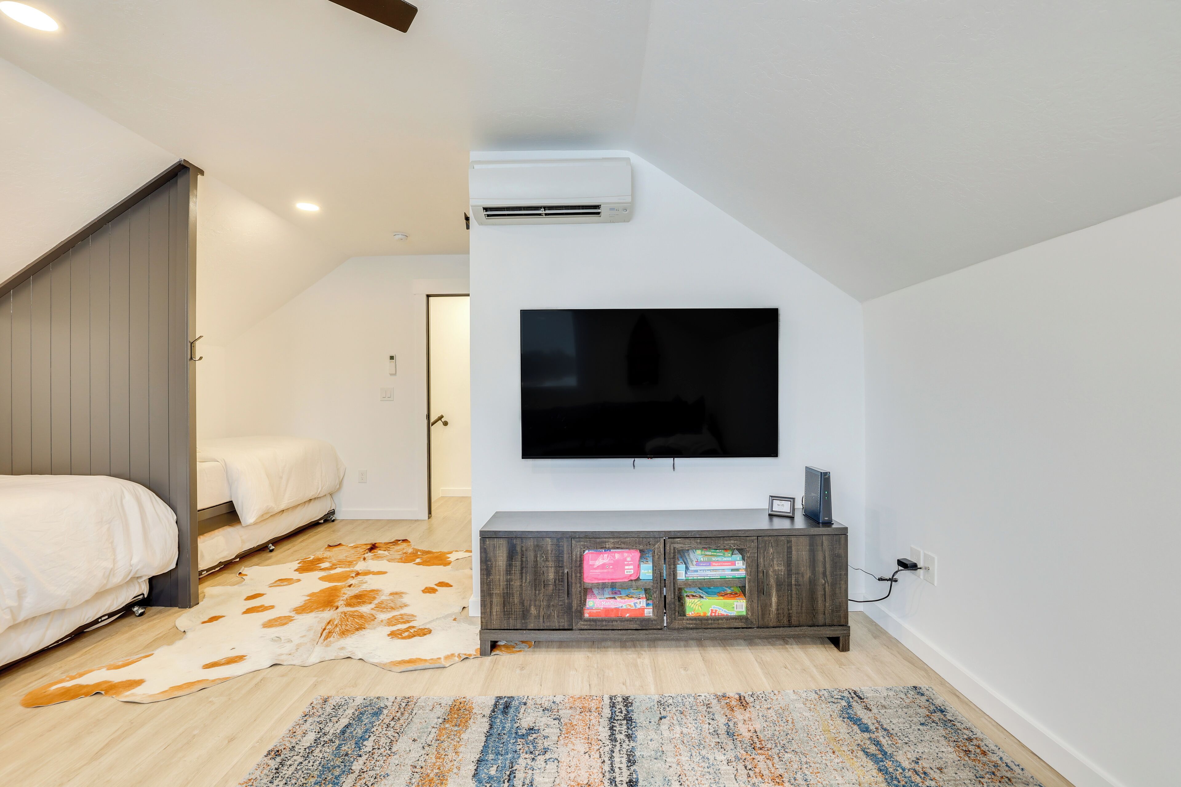 Een moderne slaapkamer met een grote televisie, een houten garderobe en een koperen vloerkleed.