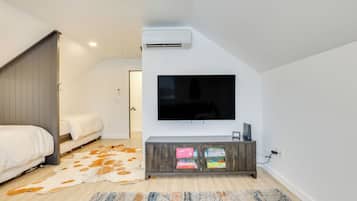 Een moderne slaapkamer met een grote televisie, een houten garderobe en een koperen vloerkleed.
