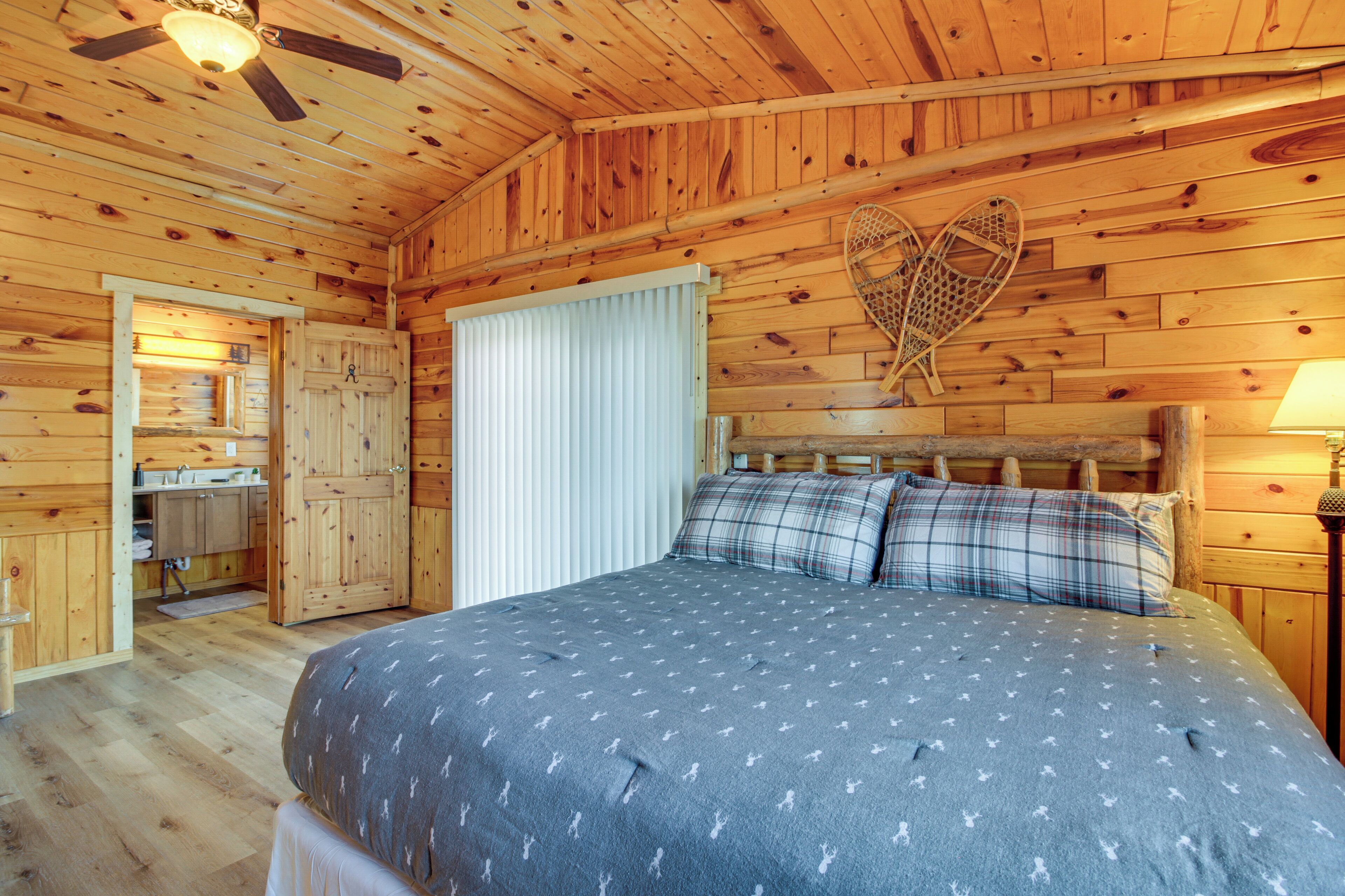 A wooden cabin bedroom with a bed, a ceiling fan, and a heart-shaped wall decoration.