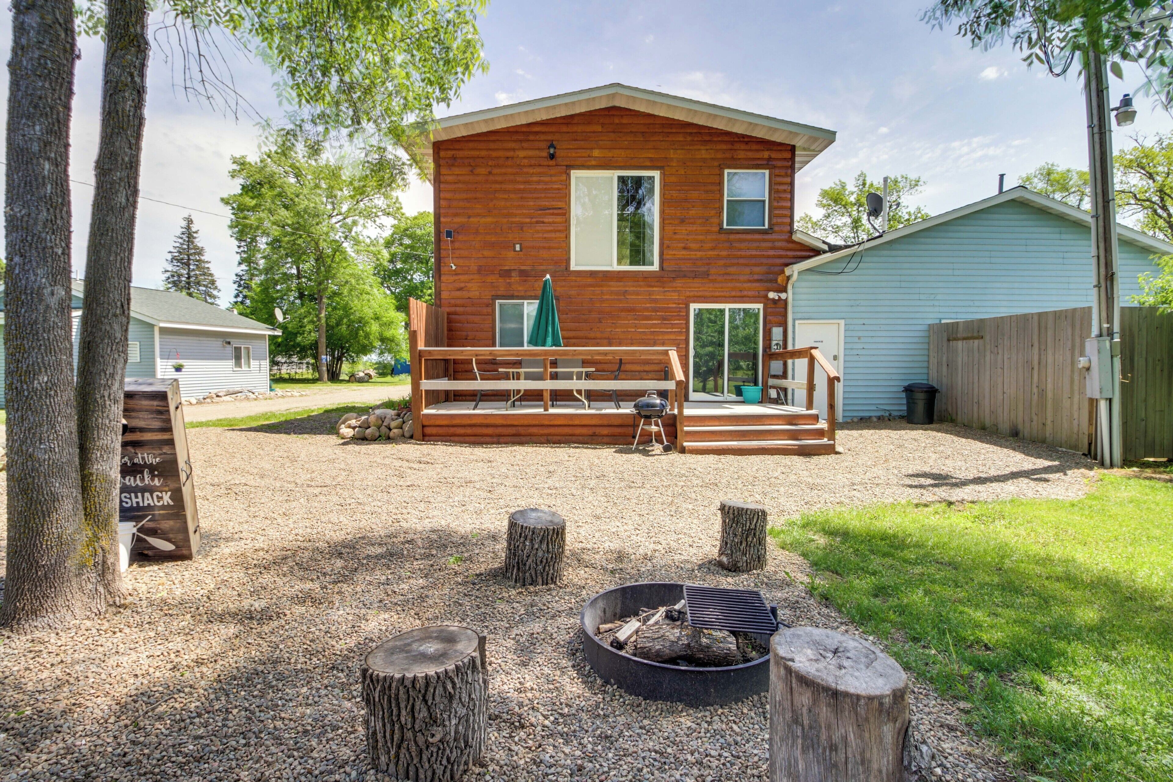 A wooden cabin with a deck, a fire pit, and a sign indicating a 'Shack at the Shack'.