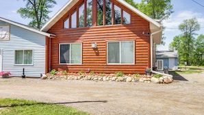 A log cabin with a gabled roof, two large windows, and a small porch area. - Eagle's Nest Cabin on Mille Lacs Lake: Boat + Fish (Garrison)