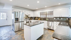 A modern kitchen with white cabinets, stainless steel appliances, and a granite countertop island. - Near Lake Fork: Home w/ Fire Pit in Yantis! (Yantis)