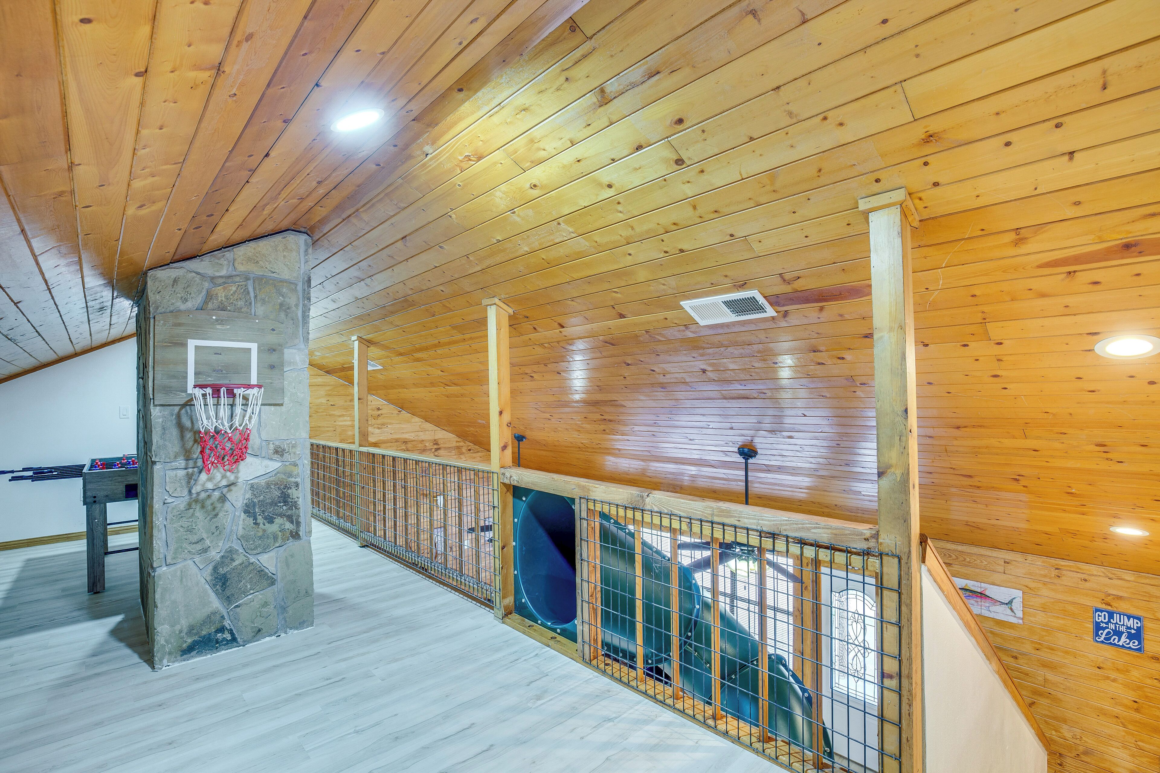 A wooden interior with a basketball hoop, a stone pillar, and a slide.