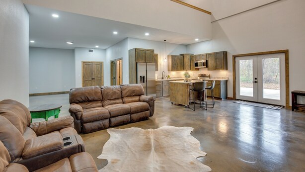 A spacious living area with a leather sofa, a large fur rug, and a kitchen in the background. - Peaceful Yantis Retreat - 1 Mi to Lake Fork! (Yantis)