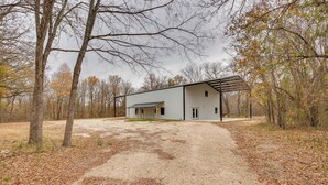 A modern two-story building with a covered porch and a dirt driveway leading to it. - Peaceful Yantis Retreat - 1 Mi to Lake Fork! (Yantis)