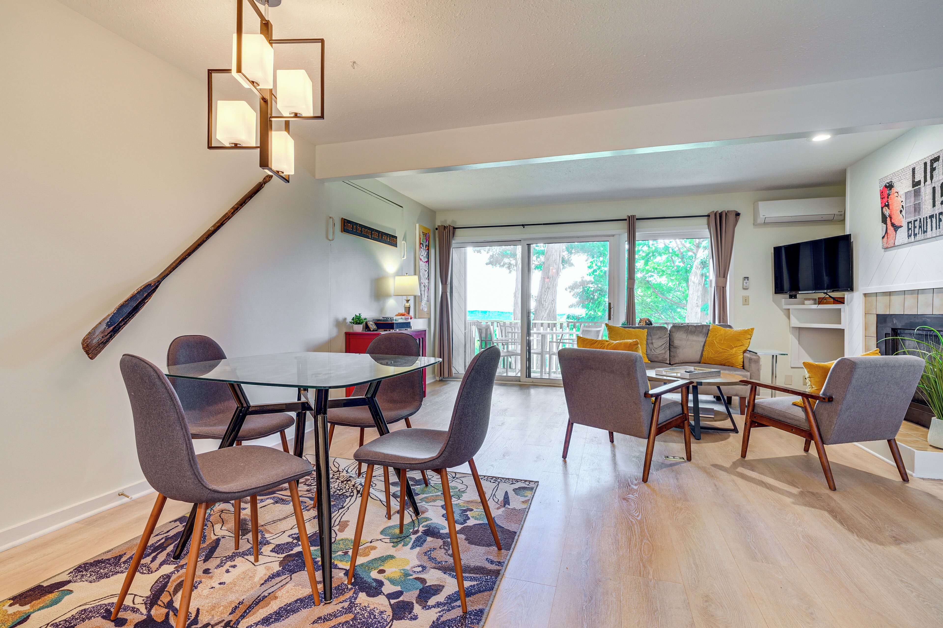 Un salon moderne avec une table à manger en verre, des sièges confortables, une cheminée et un balcon avec vue.