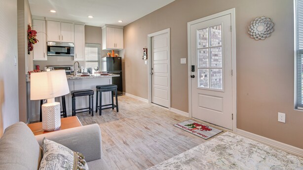 A modern kitchen with white cabinets, a black refrigerator, and a dining area with a table and chairs. - Small Private House Near Best Places (Brownsville)