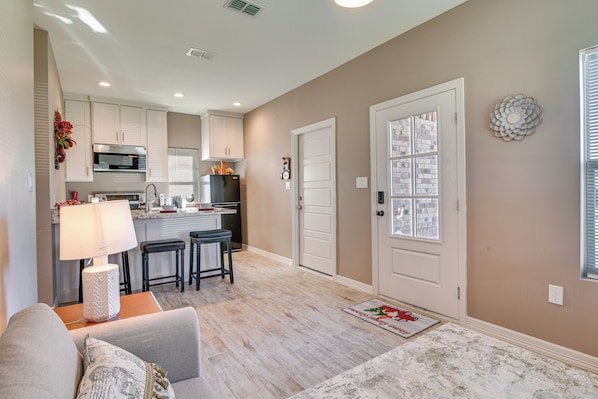 A modern kitchen with white cabinets, a black refrigerator, and a dining area with a table and chairs.