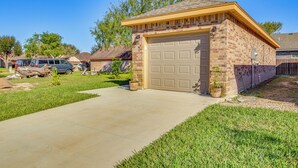 A single-story brick garage with a beige garage door, a concrete driveway, and a small lawn area. - Small Private House Near Best Places (Brownsville)