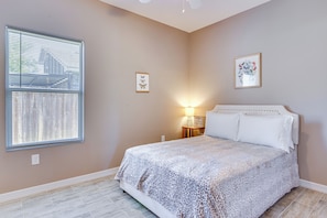A bedroom with a bed, a nightstand, a wall-mounted lamp, and two framed pictures. - Pet-friendly Brownsville Apartment w/ Yard! (Brownsville)