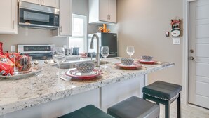 A modern kitchen with a central island, stainless steel appliances, and a decorative clock on the wall. - Small Private House Near Best Places (Brownsville)