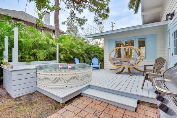 Relax on the deck with a hot tub, rocking chair, and comfortable seating amidst lush greenery.