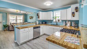 A modern kitchen with white cabinets, a wooden countertop, and a dishwasher. - Gulfport Vacation Rental w/ Patio & Game Room! (Gulfport)