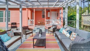 A covered outdoor patio with wicker furniture, a striped rug, and a barbecue grill. - Gulfport Vacation Rental w/ Patio & Game Room! (Gulfport)