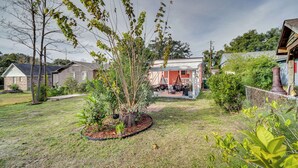 A residential backyard with a lawn, a tree, and a house with a red roof. - Gulfport Vacation Rental w/ Patio & Game Room! (Gulfport)