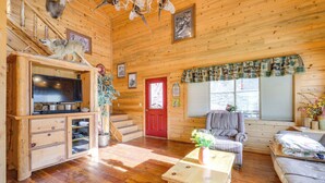 A wooden cabin interior with a TV, a fireplace, a red door, and a cozy seating area. - Pet-friendly Idaho Home on the Salmon River! (Salmon)