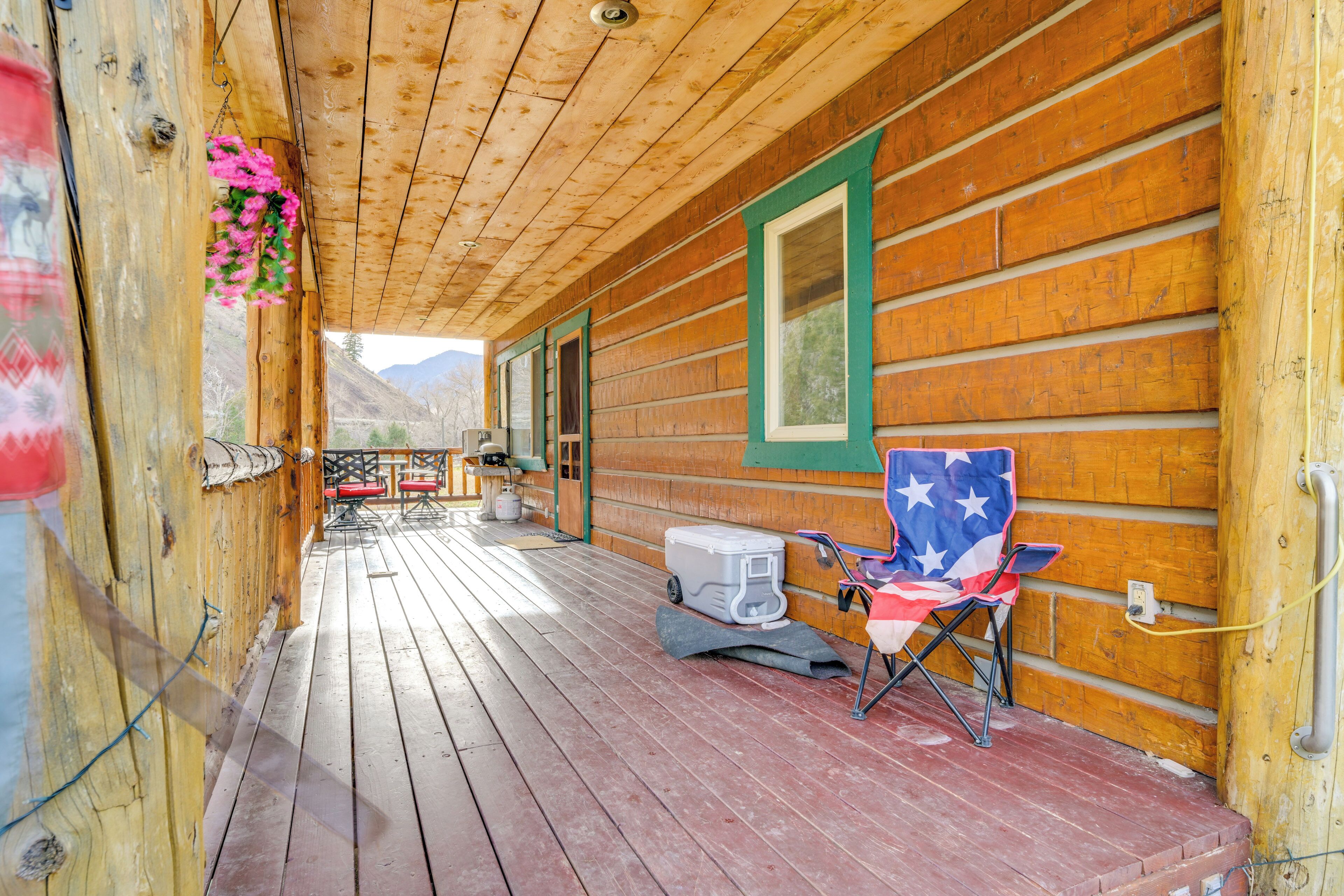 A wooden cabin with a porch, a folding chair, and a cooler.