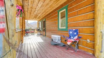 A wooden cabin with a porch, a folding chair, and a cooler.