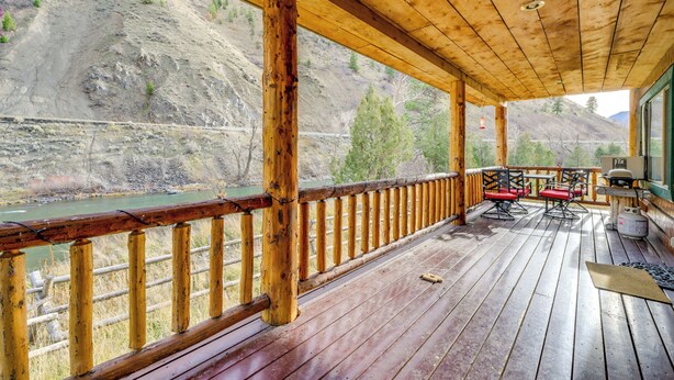 A wooden deck with a view of a river and hills. - Pet-friendly Idaho Home on the Salmon River! (Salmon)