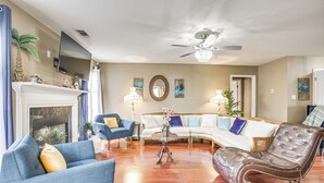 Un salon doté d’une cheminée, d’un téléviseur, d’un ventilateur de plafond et de différents types de sièges.