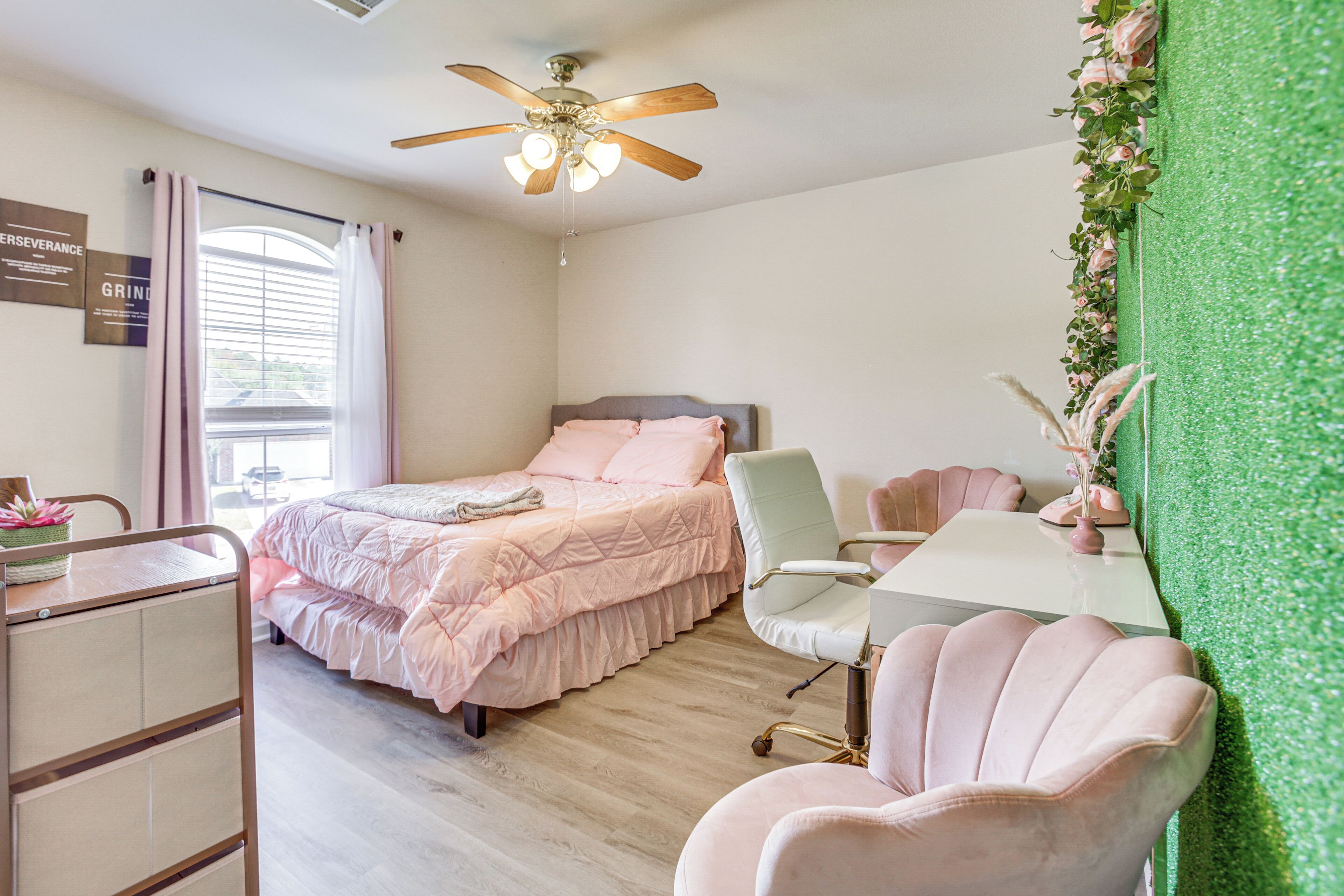 A bedroom with a bed, desk, chair, and a green wall.