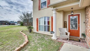 Une maison avec un porche à l’avant, une pancarte de bienvenue et une boîte aux lettres.