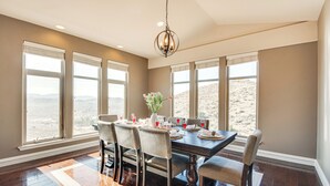 A dining area with a large table set for six, surrounded by six chairs, with a chandelier above and large windows offering a view of the desert. - Expansive Mountain Gem: Game Room, 3 Mi to Acton (Acton)