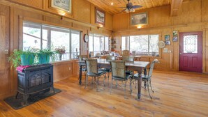 A wooden interior with a dining table, chairs, a fireplace, and large windows. - Salmon Vacation Rental w/ Mountain Views! (Salmon)