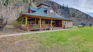 A log cabin with a porch, a mountain backdrop, and a clear sky. - Salmon Vacation Rental w/ Mountain Views! (Salmon)