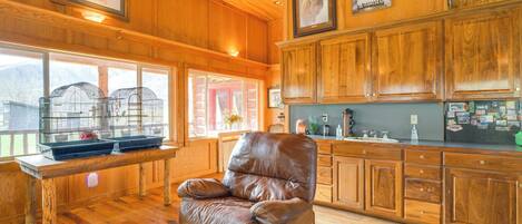 A wooden interior with a leather chair, wooden cabinets, and a window with a view.