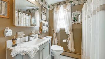 A bathroom with a vanity, sink, mirror, toilet, and shower curtain.
