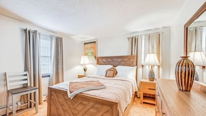A bedroom with a wooden bed, a nightstand, a lamp, a chair, and a large mirror. - Vintage Windsor Home: Private Yard & Covered Deck (Windsor)