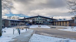 A hotel with a modern design, featuring a prominent entrance and a parking area. - Bellaire Condo - Walk to Shanty Creek Resort! (Bellaire)