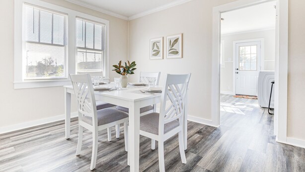 A dining area with a white table and chairs, a vase with flowers, and two framed pictures on the wall. - Quiet Grove Hill Cottage w/ Wraparound Deck! (Grove Hill)