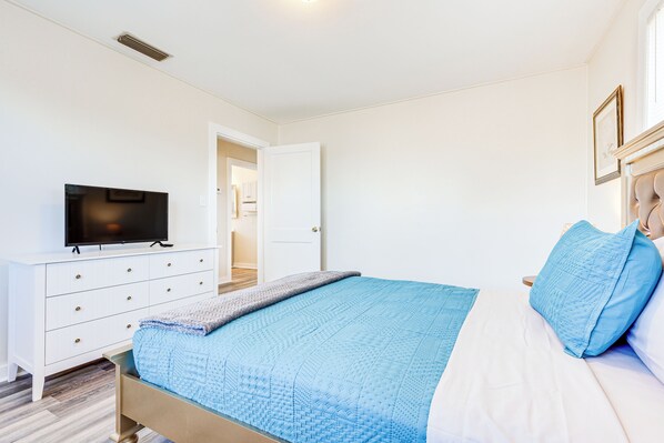 A bedroom with a bed, a TV on a dresser, and a door leading to another room. - Quiet Grove Hill Cottage w/ Wraparound Deck! (Grove Hill)