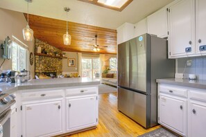 Una cocina con una isla grande, electrodomésticos de acero inoxidable y vigas de techo de madera.