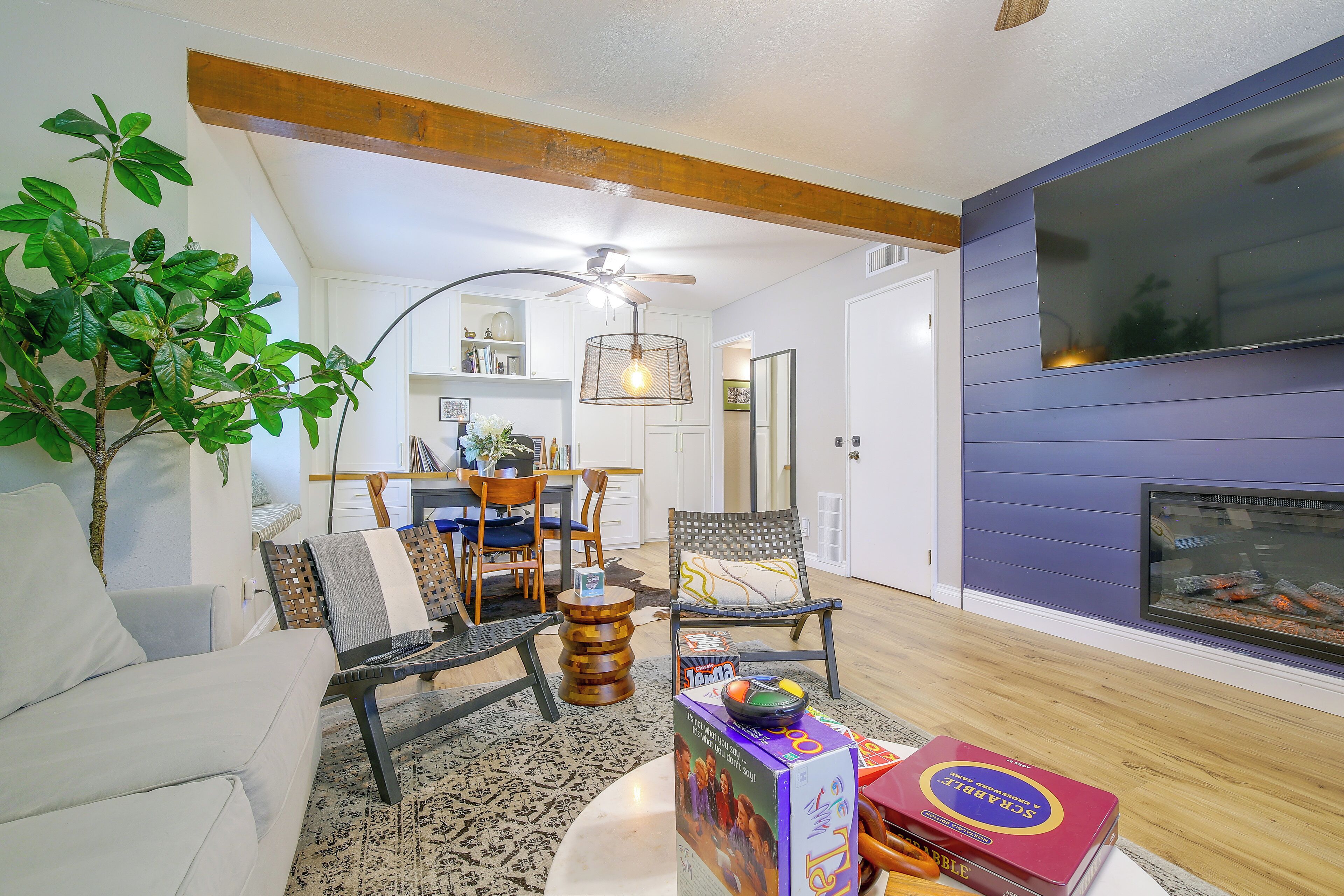 A living room with a fireplace, a dining area, and a kitchen in the background.