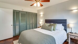 Ein Schlafzimmer mit Bett, Deckenventilator, Nachttisch und Kleiderschrank.