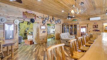 A rustic interior with wooden floors, a long dining table, and a fireplace.
